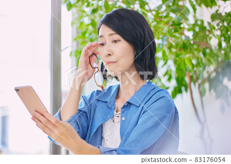 Middle-aged women with presbyopia who have difficulty seeing smartphones 83176054