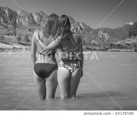 Two girls stay in river on mountains background Two girls stay in river on mountains background 83176590