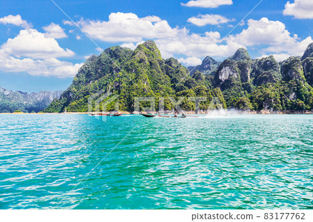 Wooden Thai traditional long-tail boat on a lake with mountains at Ratchaprapha Dam, Thailand 83177762