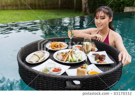 cheerful woman enjoying with floating food in swimming pool cheerful woman enjoying with floating food in swimming pool 83178332