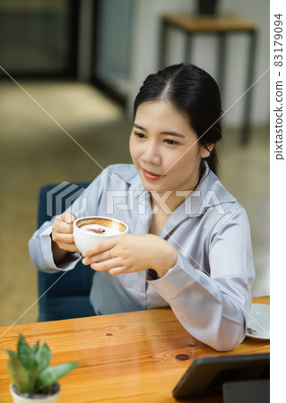 Happy young businesswoman enjoying her afternoon coffee 83179094
