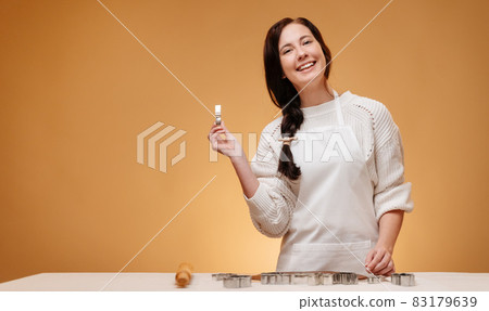 Cheerful woman makes Christmas baking cookies using metal molds. Cheerful woman makes Christmas baking cookies using metal molds. 83179639