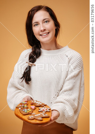 Happy woman holds a tray with fresh pastry pastries for christmas. 83179656