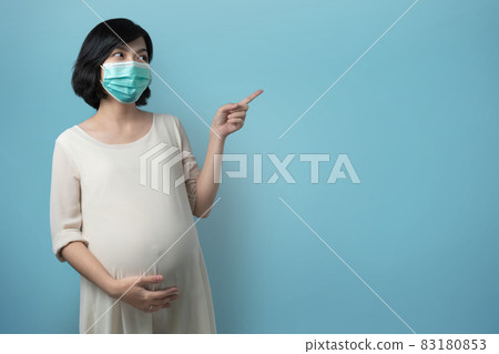 Portrait of Asian Pregnant woman wearing medical face mask on blue isolated background. Portrait of Asian Pregnant woman wearing medical face mask on blue isolated background. 83180853