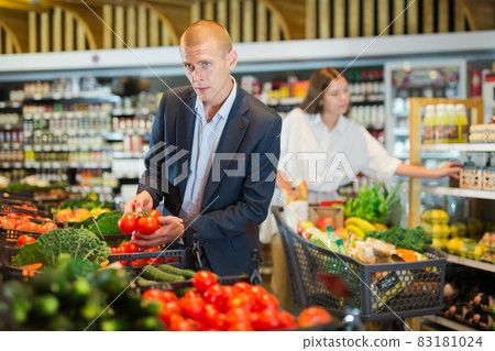 Young confident man selects fresh vegetables in the supermarket 83181024