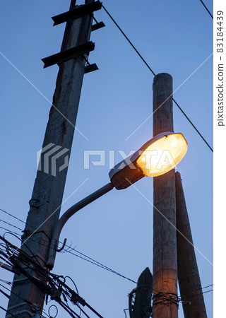 Yellow lantern on a concrete pole against the background of the dark sky. Yellow lantern on a concrete pole against the background of the dark sky. 83184439