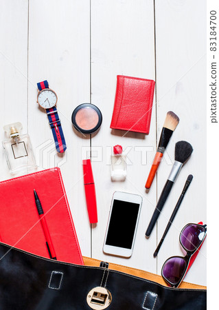 Cosmetics and women's accessories fell out of the black handbag on white background. 83184700