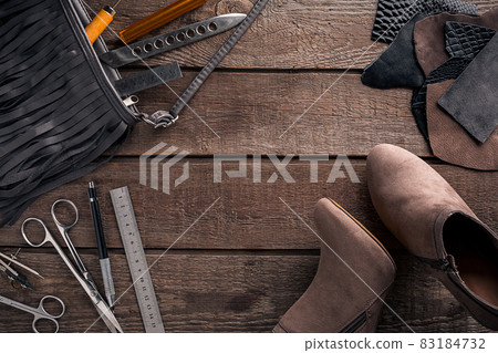 Leather craft or leather working. Leather working tools and cut out pieces of leather on work desk . 83184732