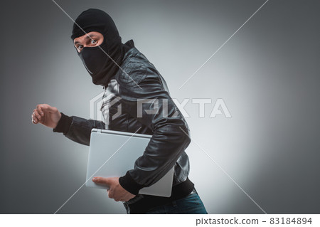 Thief stealing a laptop computer. Isolated on gray background Thief stealing a laptop computer. Isolated on gray background 83184894