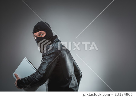 Thief stealing a laptop computer. Isolated on gray background 83184905