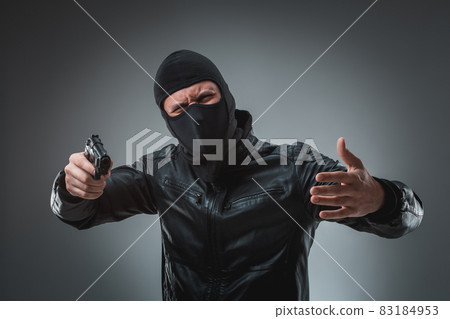 Masked robber with gun, looking into the camera. Masked robber with gun, looking into the camera. 83184953