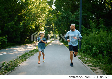 Father and son running on walking path in park 83185073