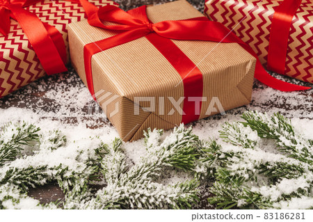 Festive gift with bow close up on wooden background with snow Festive gift with bow close up on wooden background with snow 83186281