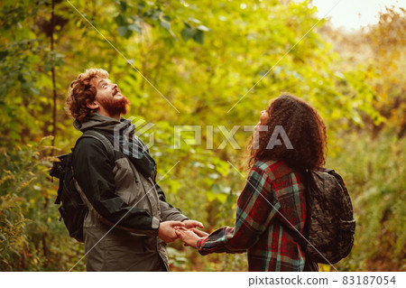 Cropped portrait of young beautiful couple spending time together in the forest on warm autumn day. Hiking activity Cropped portrait of young beautiful couple spending time together in the forest on warm autumn day. Hiking activity 83187054