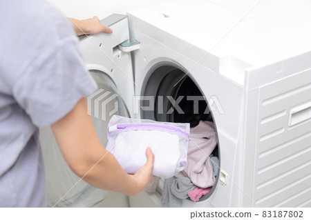 Hands of a housewife who puts it in the laundry net and does fashionable clothes washing Hands of a housewife who puts it in the laundry net and does fashionable clothes washing 83187802