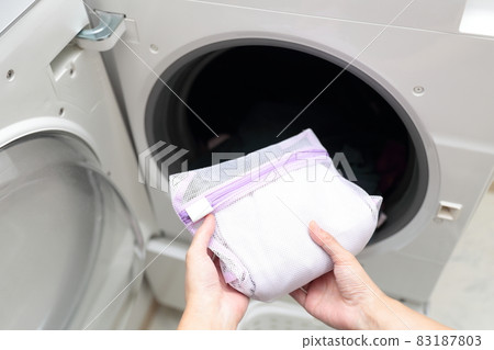 Hands of a housewife who puts it in the laundry net and does fashionable clothes washing Hands of a housewife who puts it in the laundry net and does fashionable clothes washing 83187803
