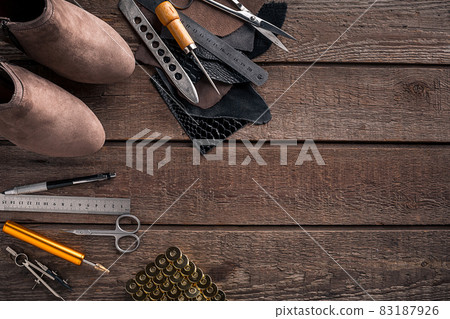 Leather craft or leather working. Leather working tools and cut out pieces of leather on work desk . 83187926