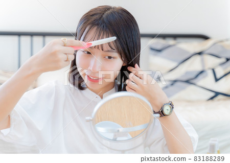 A smiling woman fixing her bangs A smiling woman fixing her bangs 83188289
