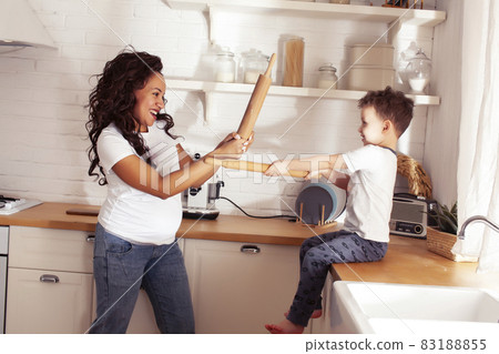 young pretty african american mother with little cute son on kitchen in morning preparing breakfast, lifestyle people concept young pretty african american mother with little cute son on kitchen in morning preparing breakfast, lifestyle people concept 83188855