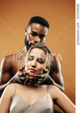 Young pretty couple diverse races together posing sensitive on brown background, lifestyle people concept Young pretty couple diverse races together posing sensitive on brown background, lifestyle people concept 83189006