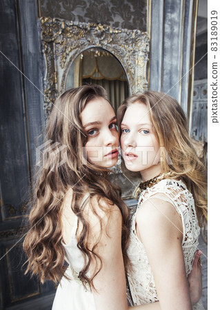 two pretty twin sister blond curly hairstyle girl in luxury house interior together, rich young people concept two pretty twin sister blond curly hairstyle girl in luxury house interior together, rich young people concept 83189019