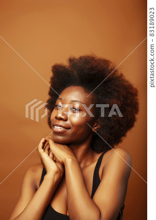 pretty young african american woman with curly hair posing cheerful gesturing on brown background, lifestyle people concept pretty young african american woman with curly hair posing cheerful gesturing on brown background, lifestyle people concept 83189023
