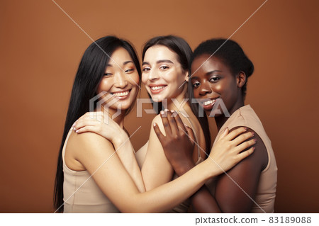 young pretty caucasian, afro, scandinavian woman posing cheerful together on brown background, lifestyle diverse nationality people concept 83189088