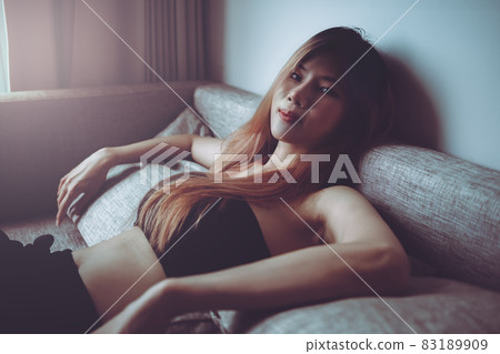 Sporty Asian woman is posing cool on sofa with seductive active black clothing for Street Girl fashion style. Sporty Asian woman is posing cool on sofa with seductive active black clothing for Street Girl fashion style. 83189909