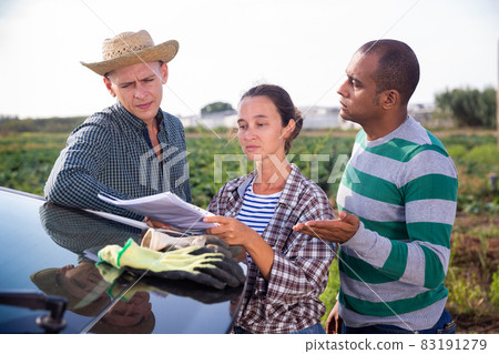 Farmers with papers standing near car on farm field, talking about some current issues 83191279