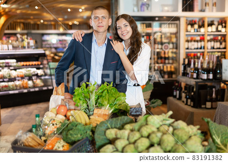 Portrait of a happy young couple with products in a cart in the supermarket 83191382