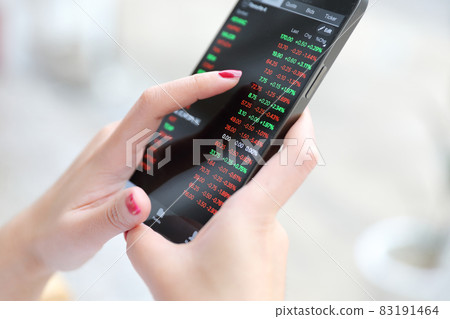Female hand with smartphone trading stocks online in coffee shop Business concept Female hand with smartphone trading stocks online in coffee shop Business concept 83191464