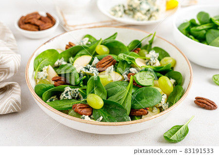 Salad of spinach, pear, grape, pecan and gorgonzola cheese with lemon dressing. Healthy food, diet. 83191533