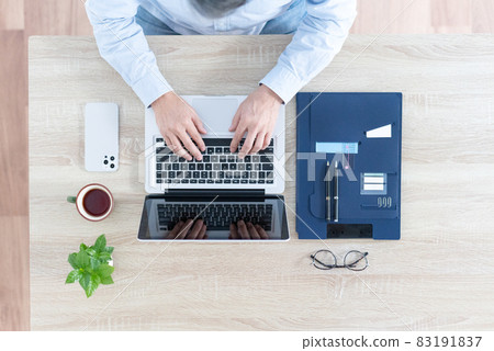 A bird's-eye view of a man hitting a laptop 83191837