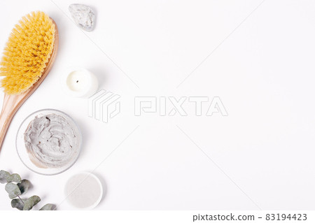 Cosmetic clay mask next to massage brush 83194423