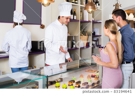 Cheerful pastry man is serving visitors Cheerful pastry man is serving visitors 83194641