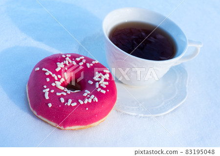 Cup of tea for breakfast with donuts on snow background 83195048