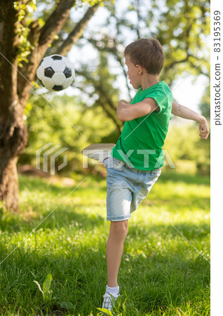 Energetic boy kicking soccer ball back. Energetic boy kicking soccer ball back. 83195369