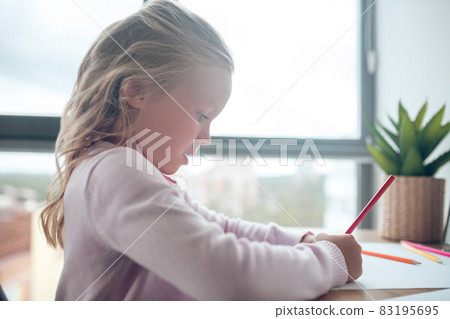 A cute girl sitting at the table and drawing A cute girl sitting at the table and drawing 83195695