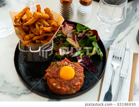 Tartar beef with quail egg and arugula served on plate. Modern French cuisine 83196930