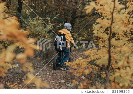 Boy on a balance bike ride in the autumn forest Boy on a balance bike ride in the autumn forest 83199365