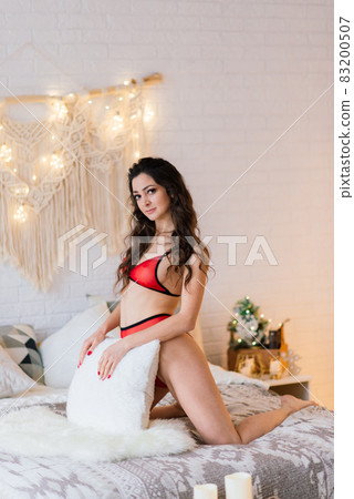 Tall slender girl in sexy lingerie alluring by the fireplace in the Christmas atmosphere. Tall slender girl in sexy lingerie alluring by the fireplace in the Christmas atmosphere. 83200507