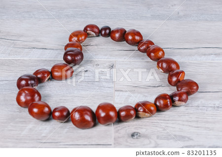 Chestnuts in a heart shape on a wooden background Chestnuts in a heart shape on a wooden background 83201135