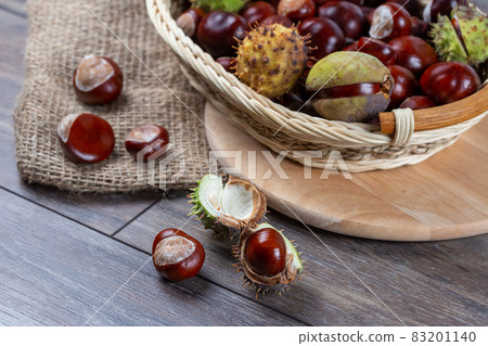 Chestnuts in a basket on a wooden background 83201140