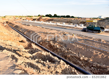 Asphalting the road and laying the sewer pipe at the construction site. Asphalt paver machine Asphalting the road and laying the sewer pipe at the construction site. Asphalt paver machine 83201862