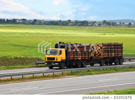 Timber truck transporting cut trees from forest along highway. Timber truck transporting cut trees from forest along highway. 83201878