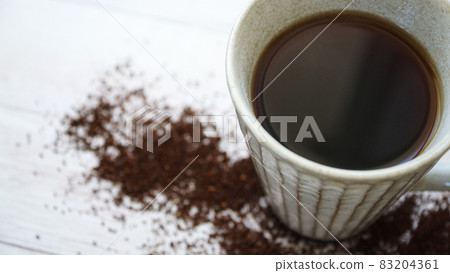 散落在木地板上的磨碎的咖啡豆和咖啡杯 散落在木地板上的磨碎的咖啡豆和咖啡杯 83204361