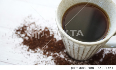 Grinded coffee beans and coffee cups scattered on the wooden floor 83204363