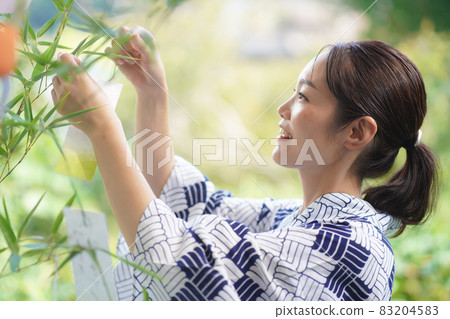 A woman wearing a strip of bamboo on Tanabata bamboo A woman wearing a strip of bamboo on Tanabata bamboo 83204583