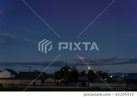 Ikaruga Town, Nara Prefecture, a harvest moon rising from the other side of the three-storied pagoda of Hokiji Temple, a World Heritage Site 83205433