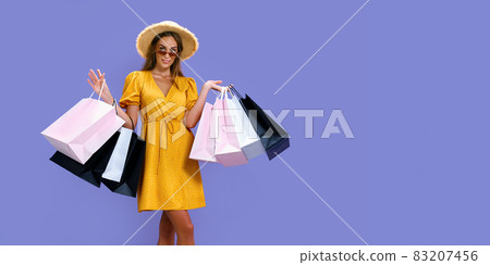 Glad woman in hat and sunglasses holds purchases while smiling at camera. Black Friday, big sales Glad woman in hat and sunglasses holds purchases while smiling at camera. Black Friday, big sales 83207456